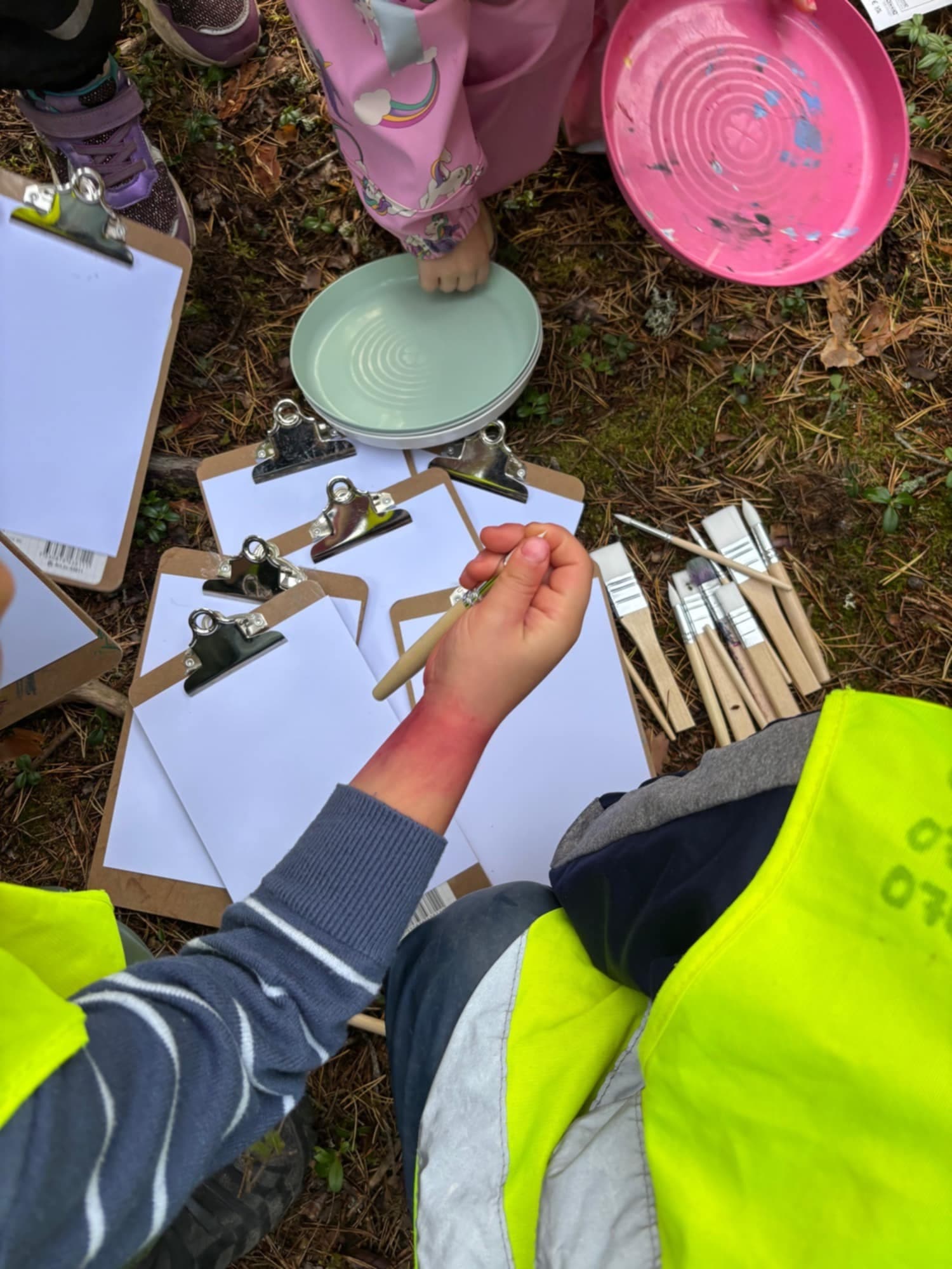 Barn som skapar med färg och penslar
